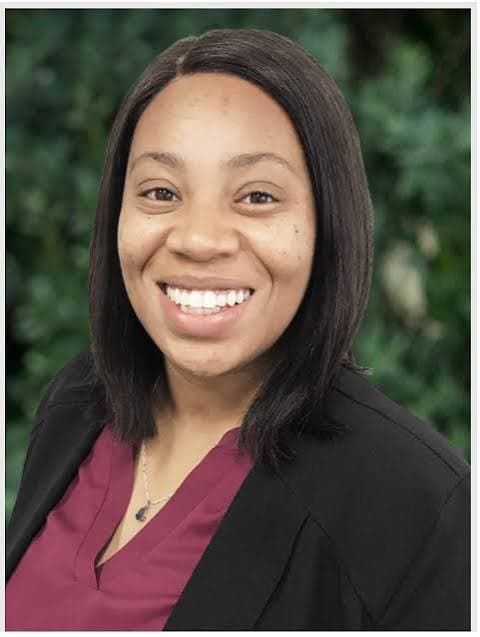 Smiling Black woman with shoulder-length dark hair, wearing a black blazer and maroon blouse.