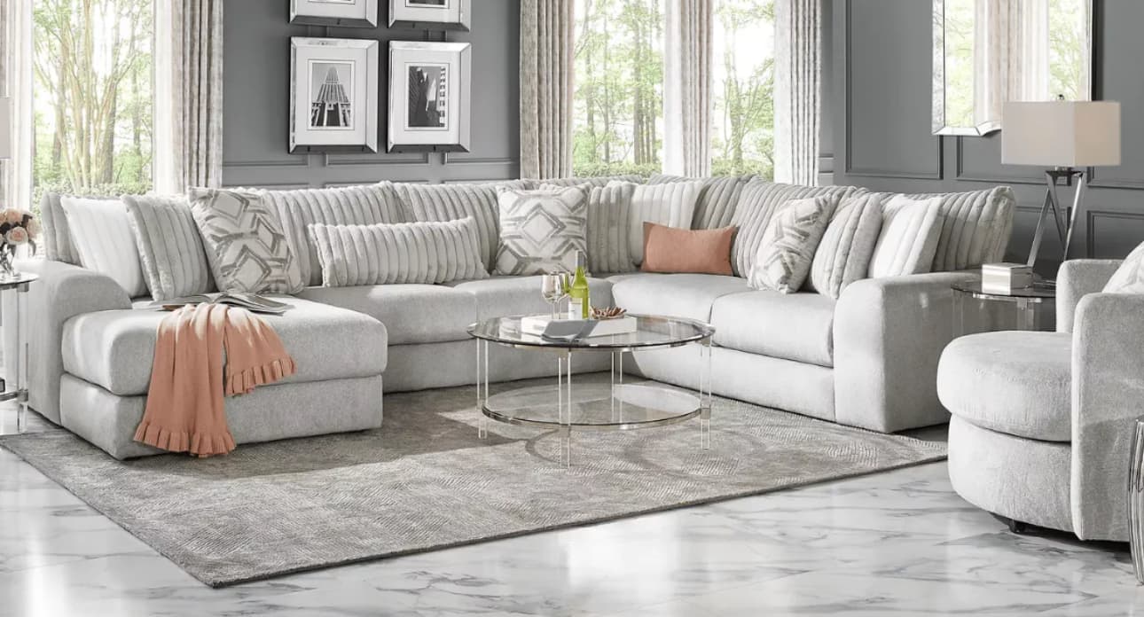 Light gray sectional sofa with peach accents and decorative pillows in a modern living room.